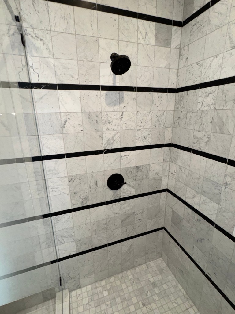 Bold black stripe shower tile in bunk room bathroom
